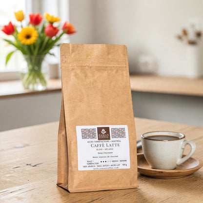 ZAMAN COFFEE Caffè Latte medium roast coffee bag with deep chocolate notes on a wooden table with a cup of coffee